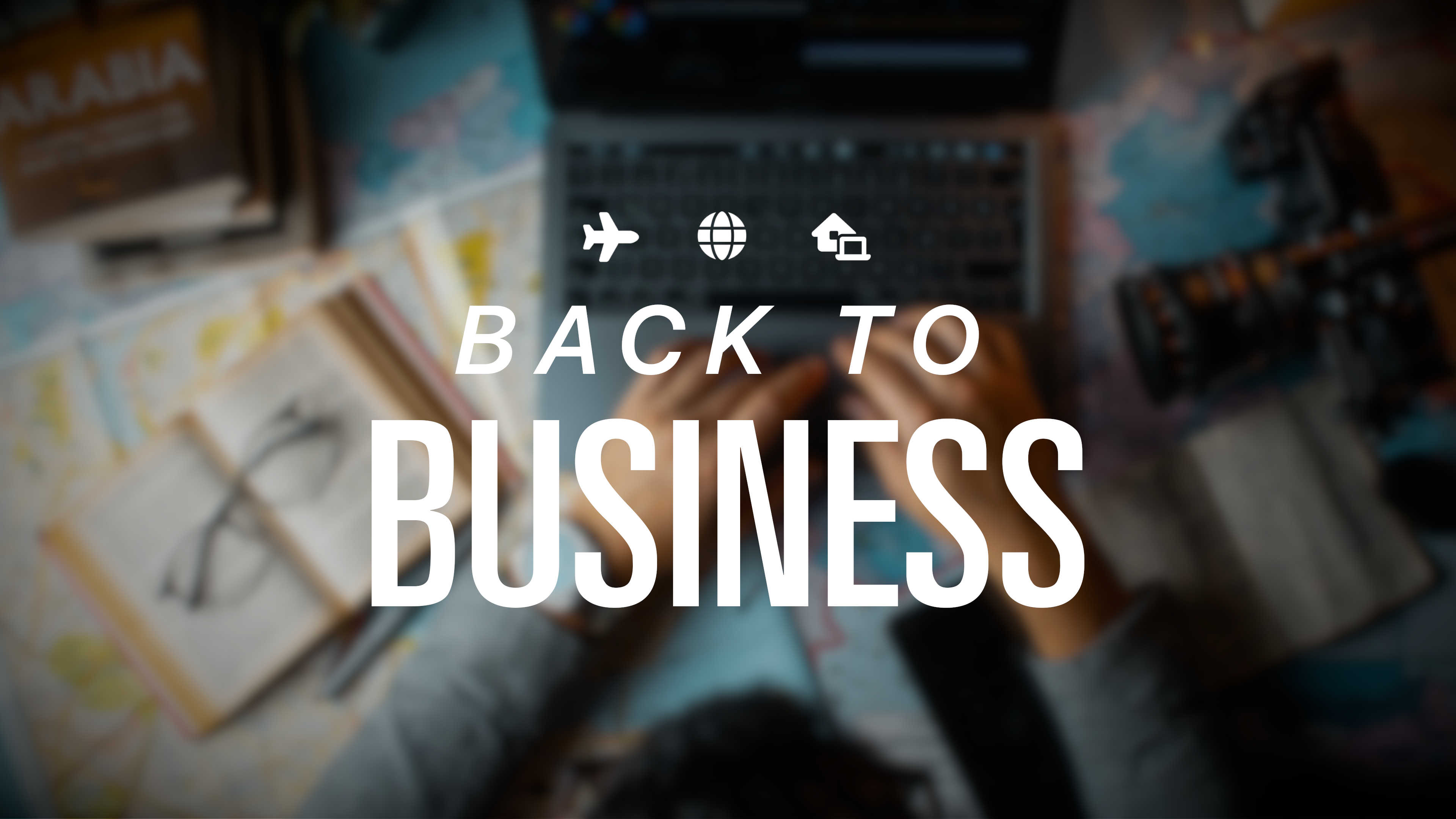 Top down image of a man at a table covered with maps, cameras, books and travel inspiration