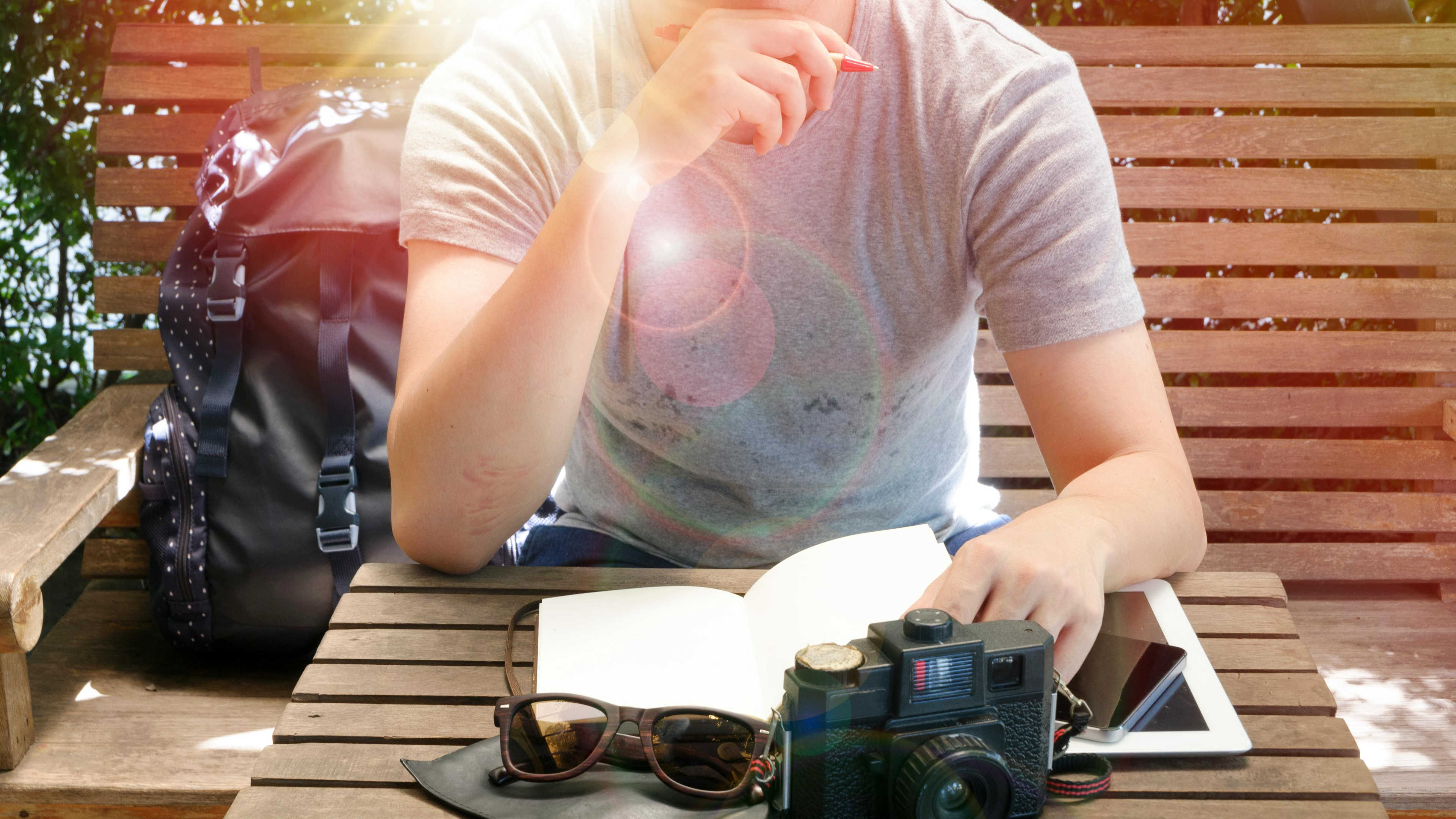A man writing in a journal at a desk in front of a computer