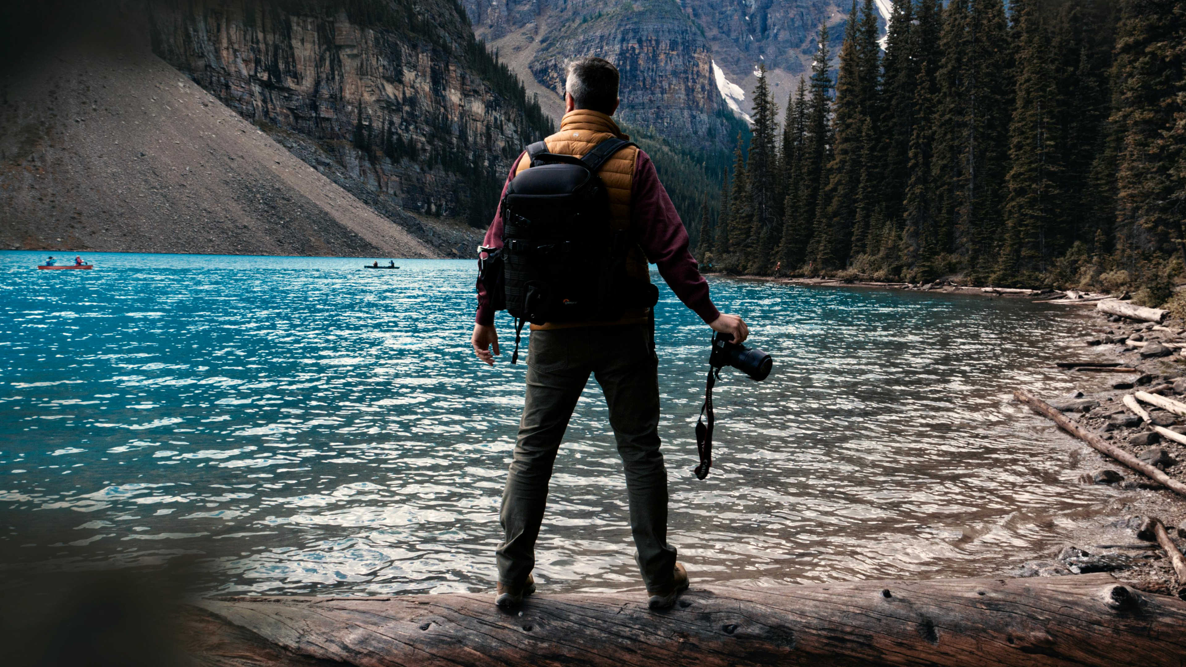 Looking through the trees at a man with a camera standing by a lake