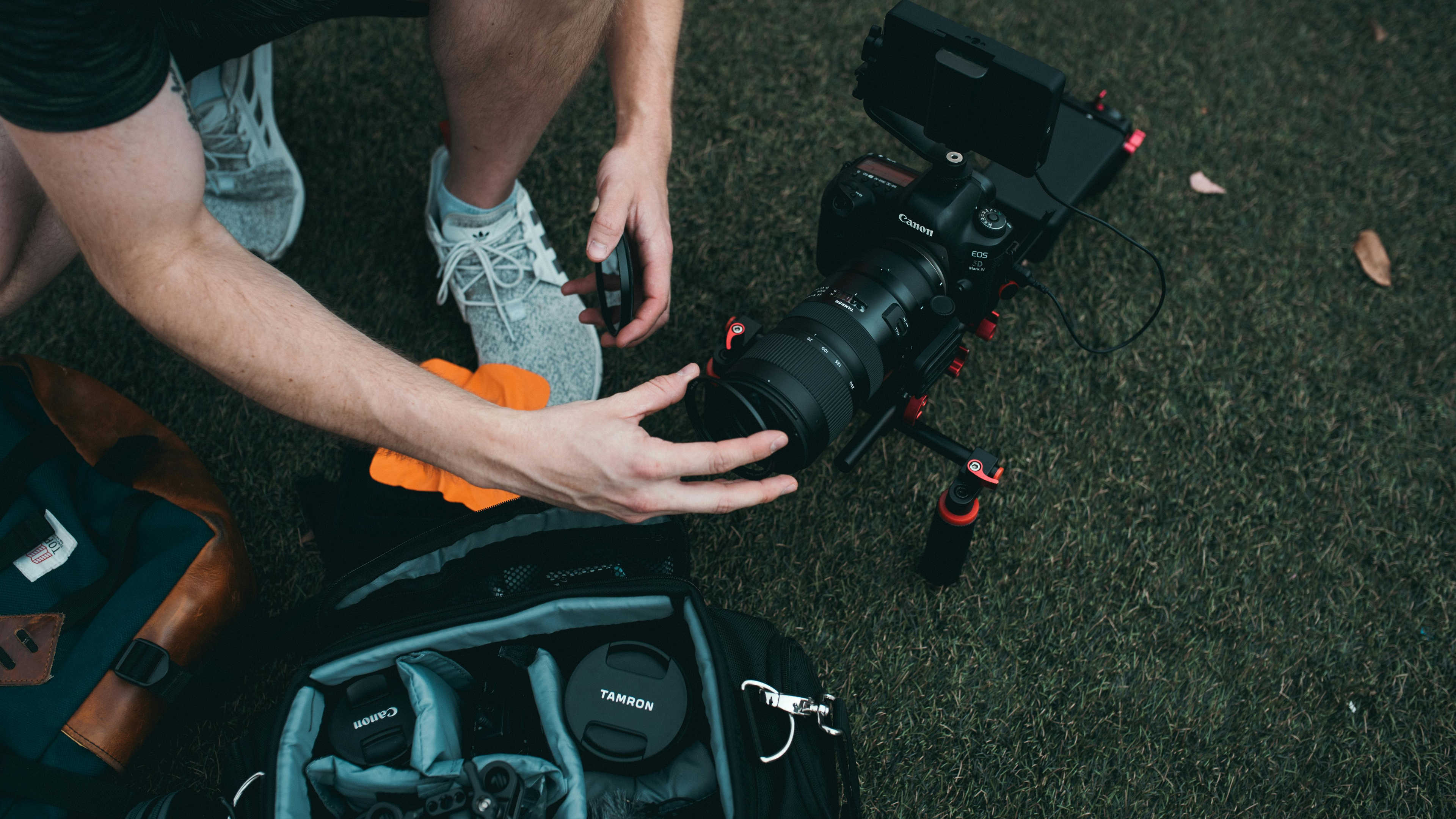 Kneeling to attach a lens cover with an open camera bag nearby