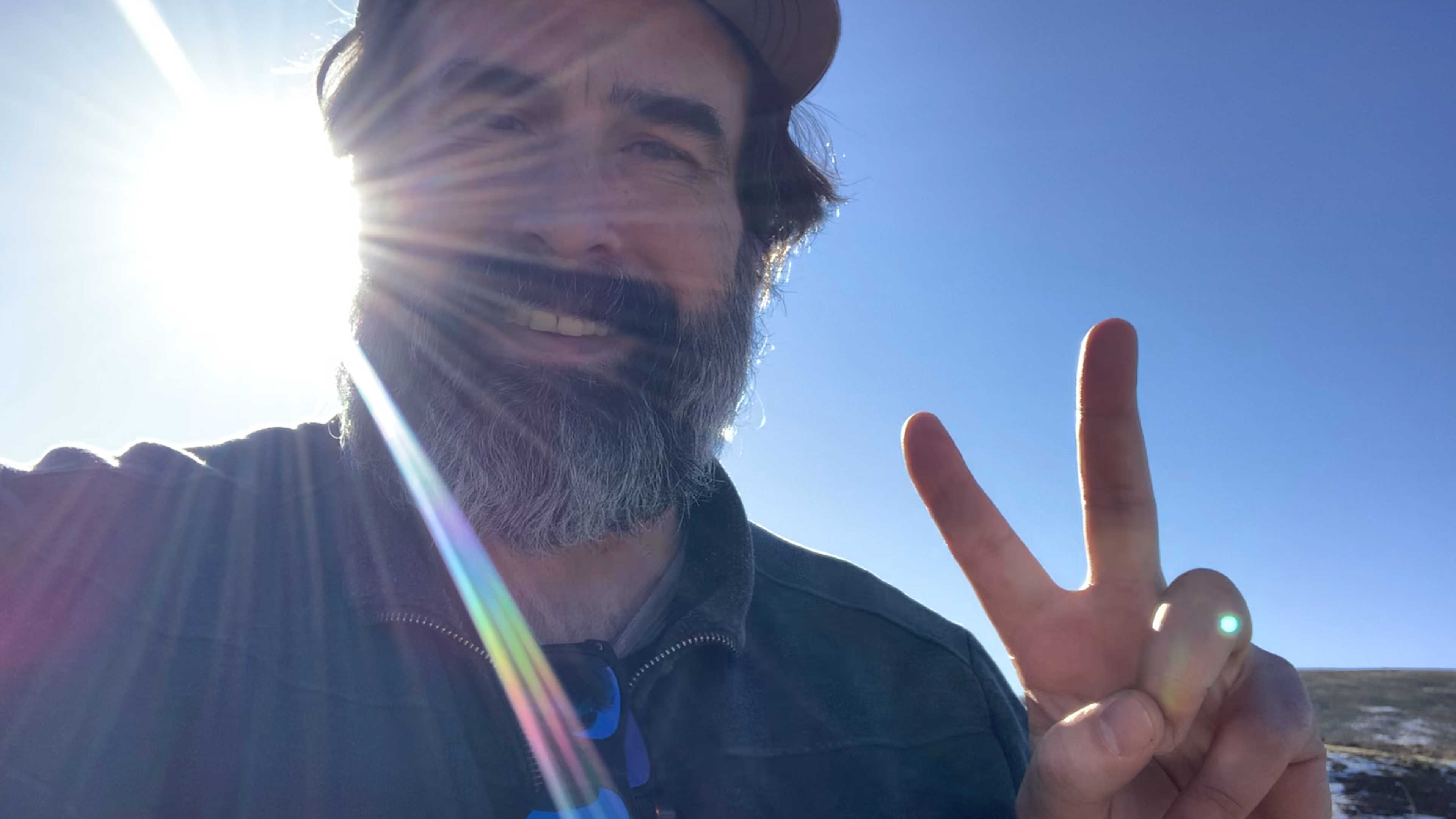 Selfie flashing the peace sign with the sun overhead in the high country
