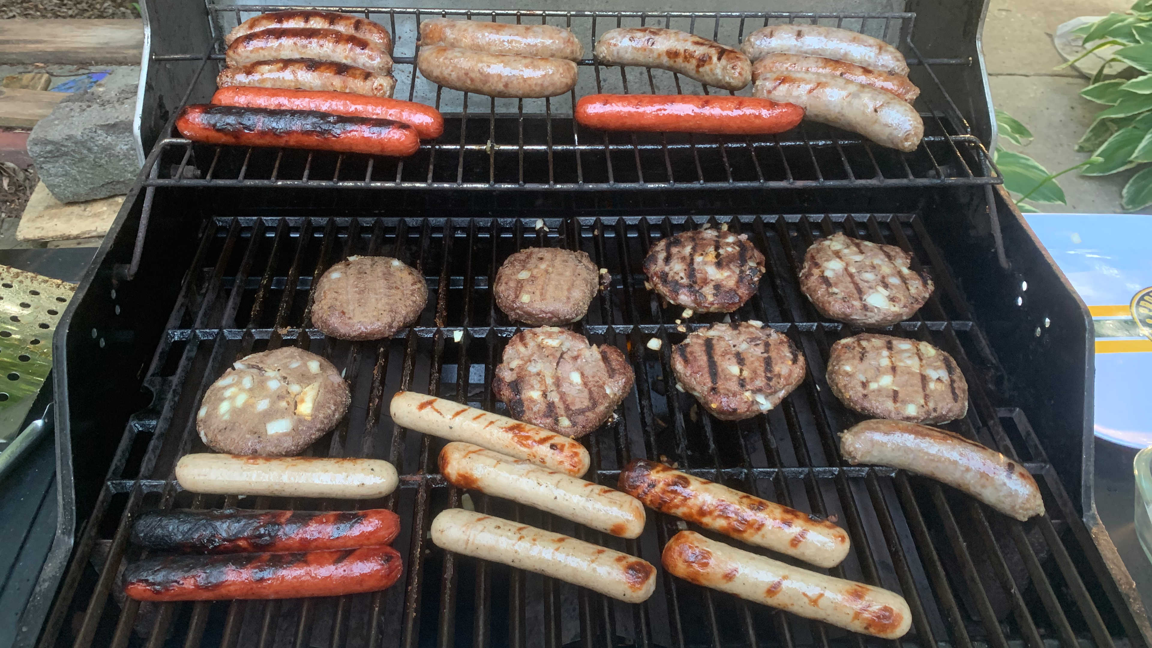 Restored grill with bratwurst and burgers cooking.